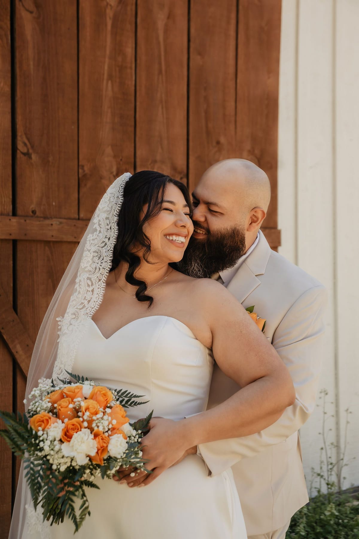 Bride in a lace veil laughing as her groom kisses her cheek at an intimate North Georgia wedding