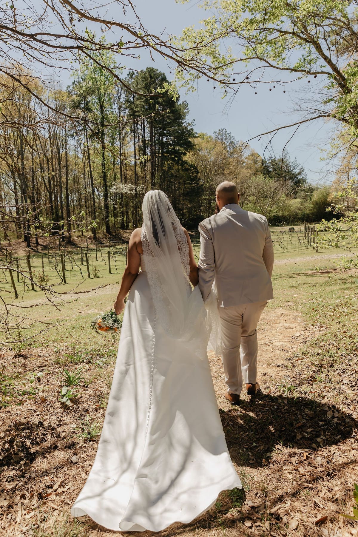 Newlyweds walking away together across a sunlit field after an intimate North Georgia wedding