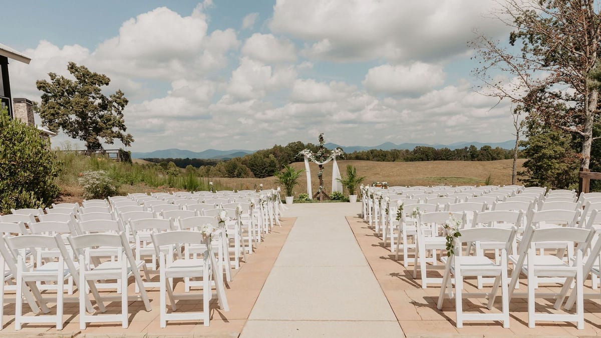 Outdoor wedding ceremony site with white chairs and a floral arch overlooking the North Georgia foothills