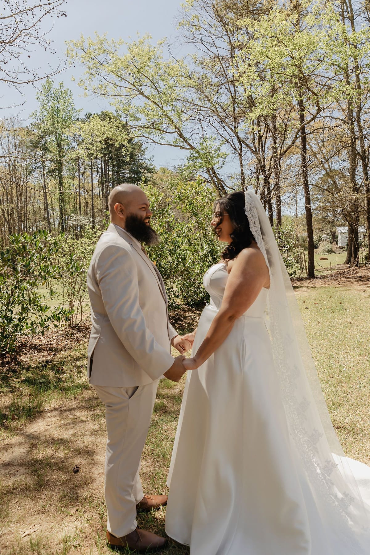 Bride and groom holding hands during their outdoor first look under spring trees in North Georgia